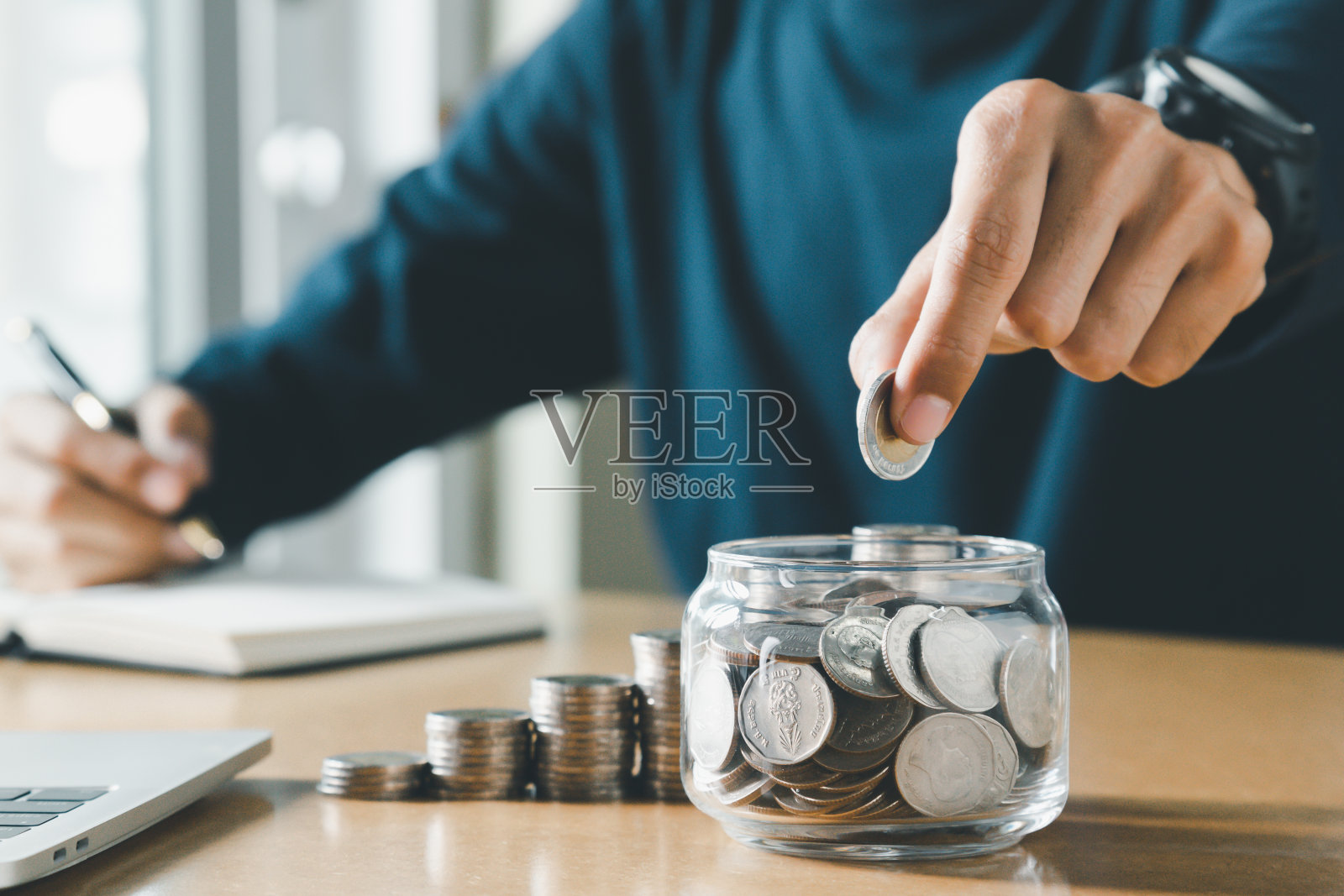 手把硬币放在存钱罐里存钱和省钱的概念。照片摄影图片