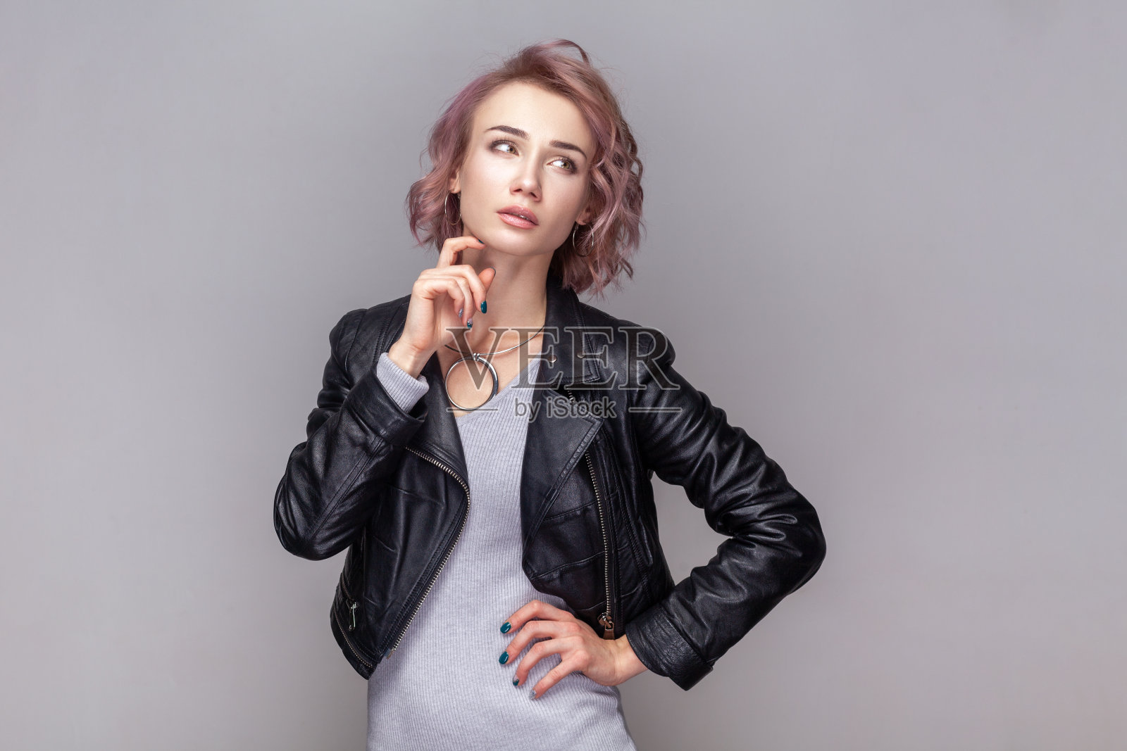 沉思、体贴的短发女人托着下巴站着，想着她的工作。照片摄影图片