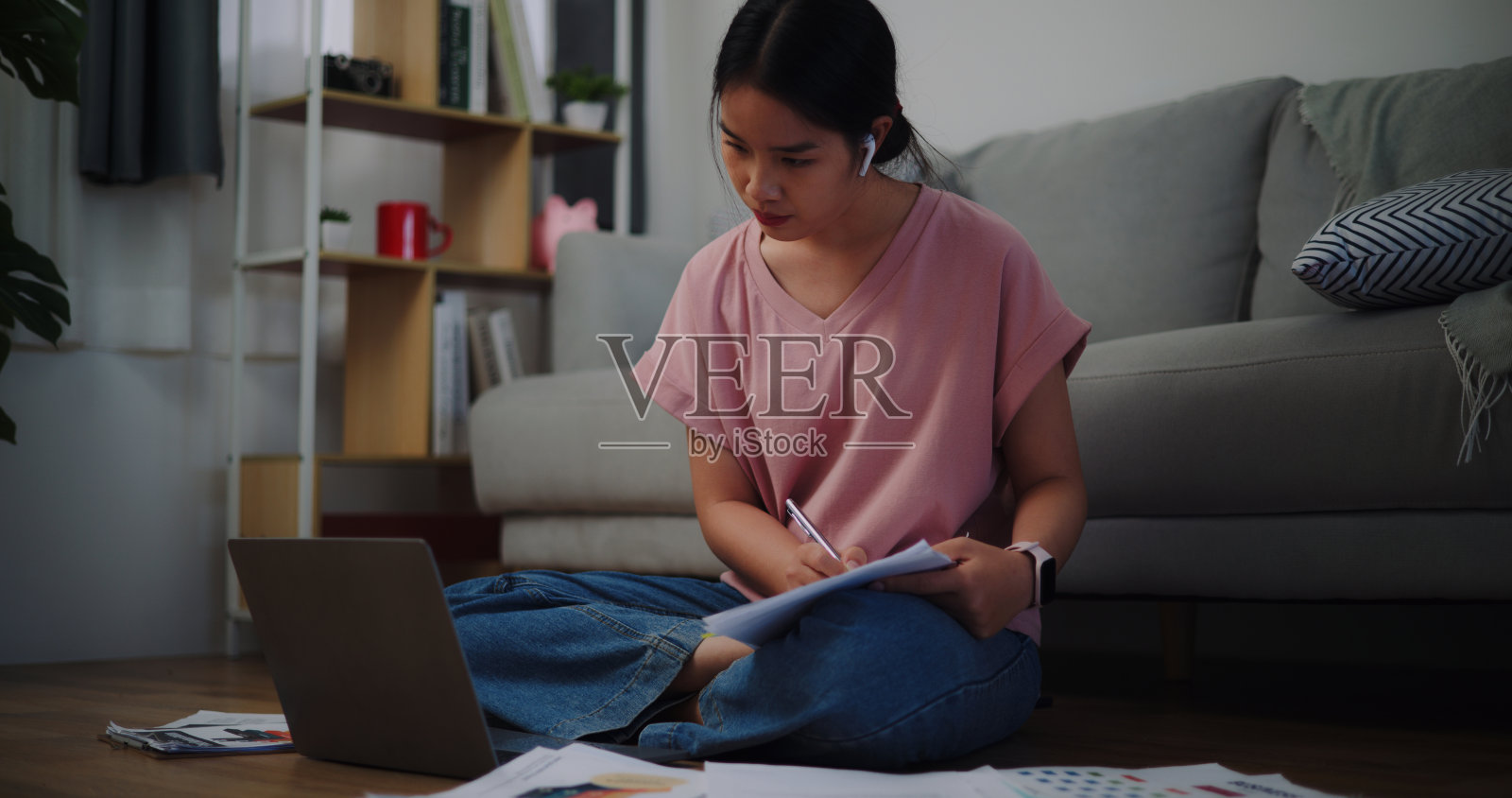 年轻女子坐在地板上用笔记本电脑在家里工作。照片摄影图片