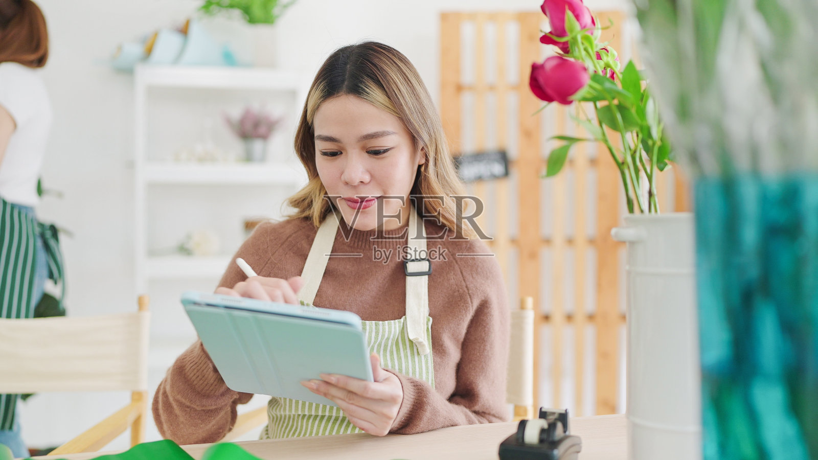 小企业的概念。年轻的亚洲女花商使用平板电脑在花店网上订购。女花商或花店老板使用平板电脑工作，在花店接受订单照片摄影图片