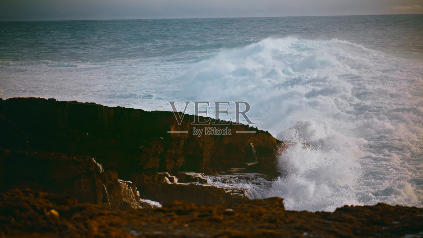 在暴风雨的日子里，海岸的海浪拍打着石头。强大的海浪冲击着海滩照片摄影图片