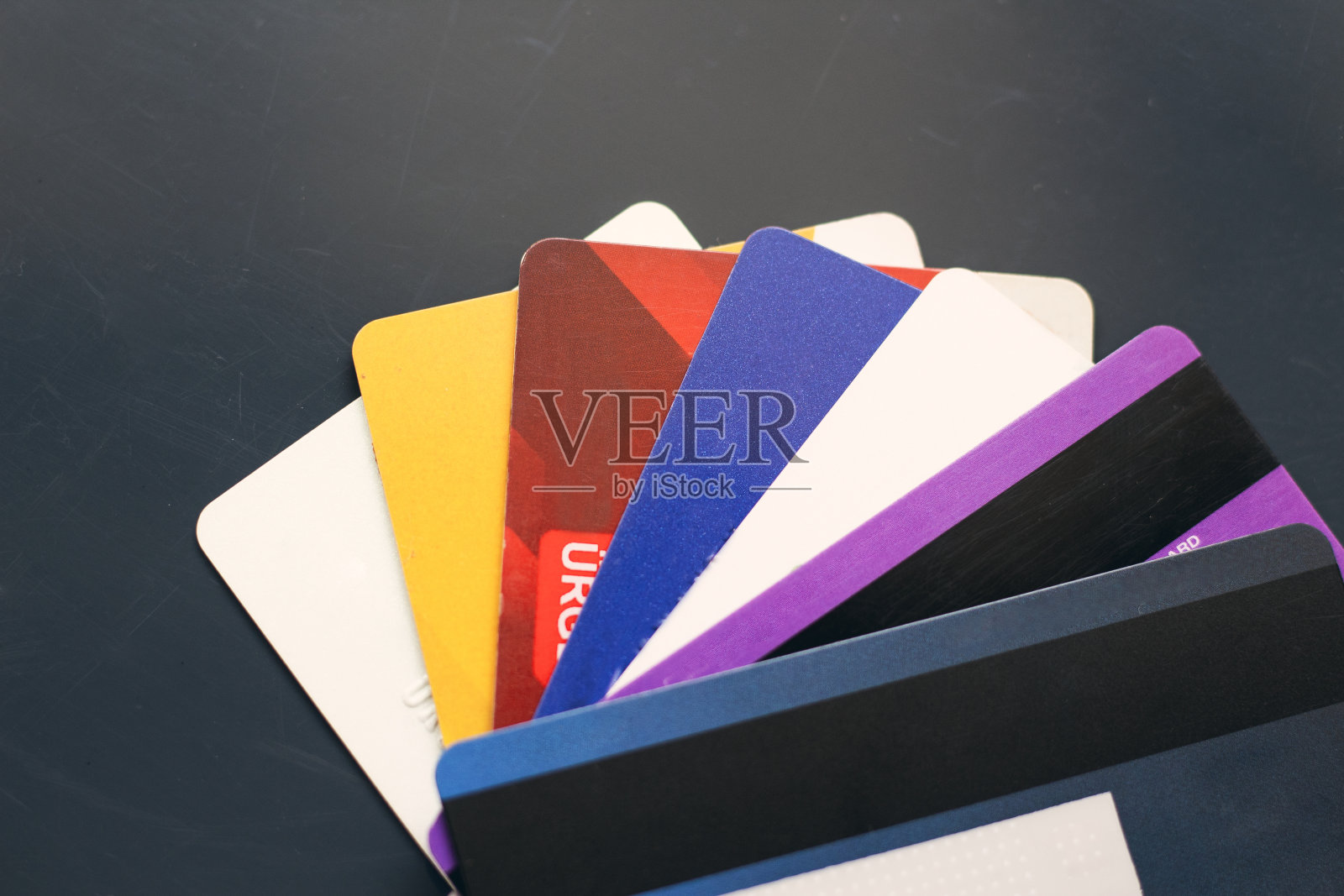 一叠黑色背景的彩色信用卡。有选择性聚焦背景的特写视图。在网上购物时用信用卡付款。照片摄影图片