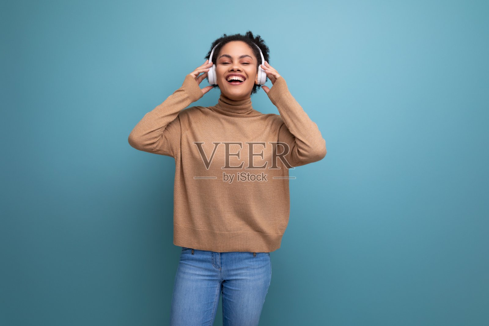 孤立的背景，可爱的年轻褐发西班牙女自由职业者戴着蓝牙耳机听音乐照片摄影图片