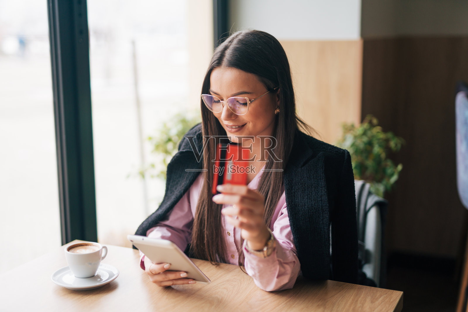 照片中，一位迷人的年轻女子在咖啡馆里使用数码平板电脑上网购物照片摄影图片