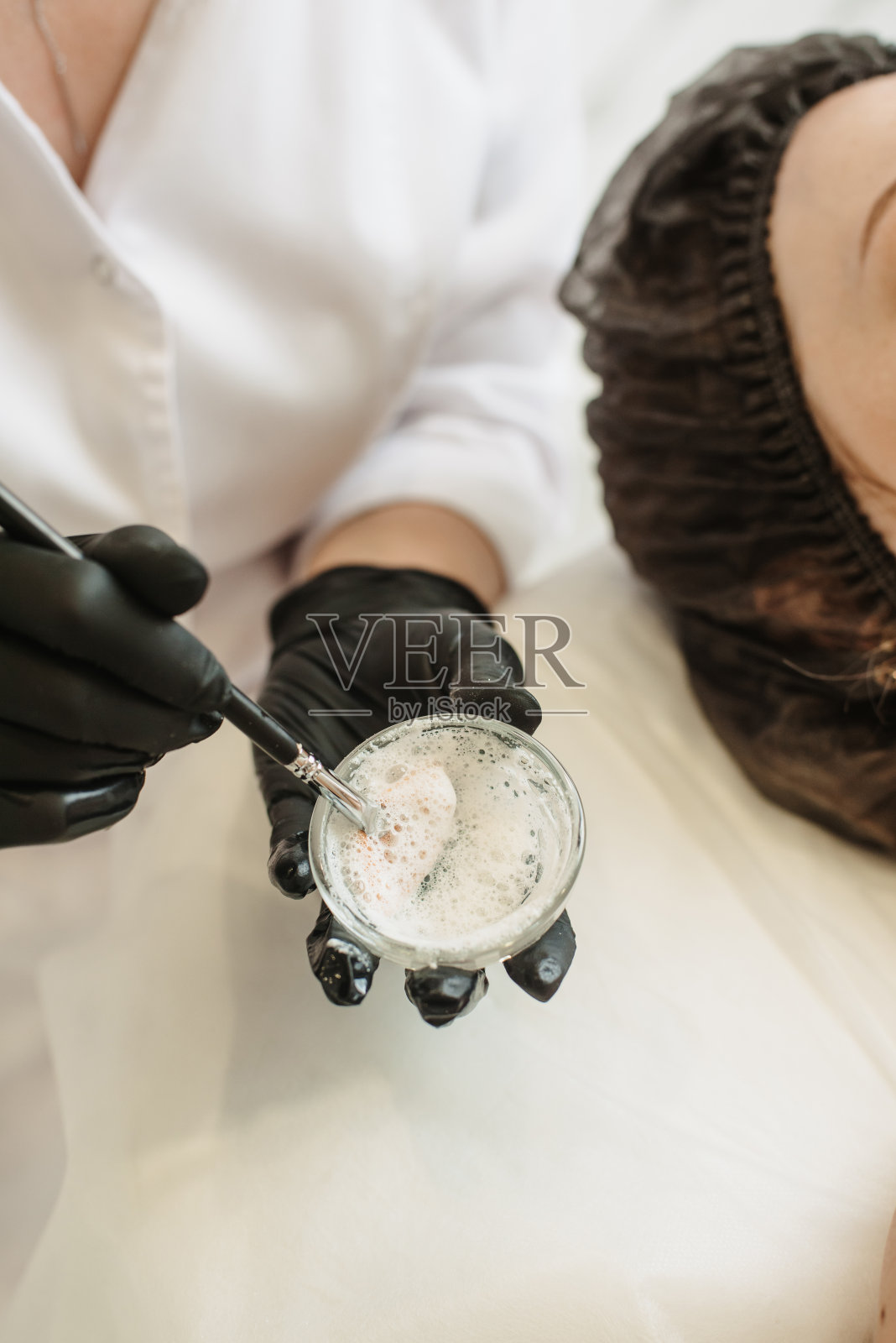 一个化妆师的手在为去皮面膜混合原料的特写照片。垂直的照片。照片摄影图片