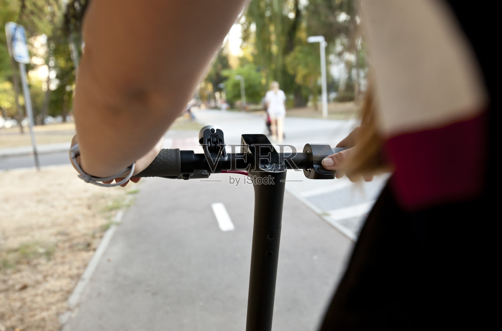 这位年轻女子骑着电动滑板车沿着小路穿过傍晚的城市照片摄影图片