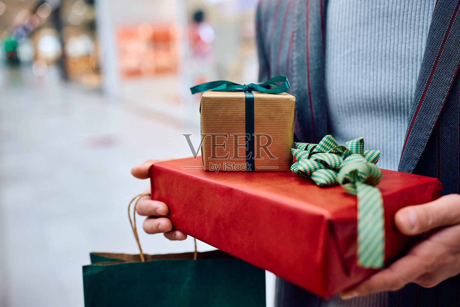 拿着包装好的礼品盒的男子特写。照片摄影图片