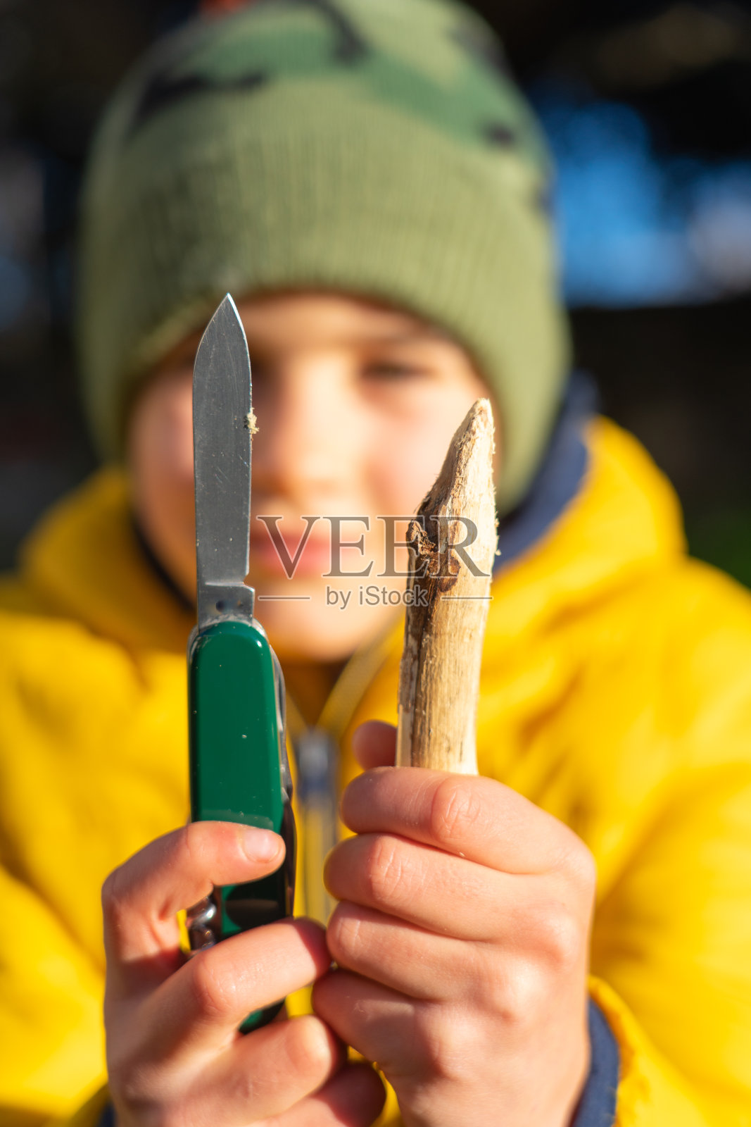 男孩展示了一根锋利的棍子和一把刀照片摄影图片