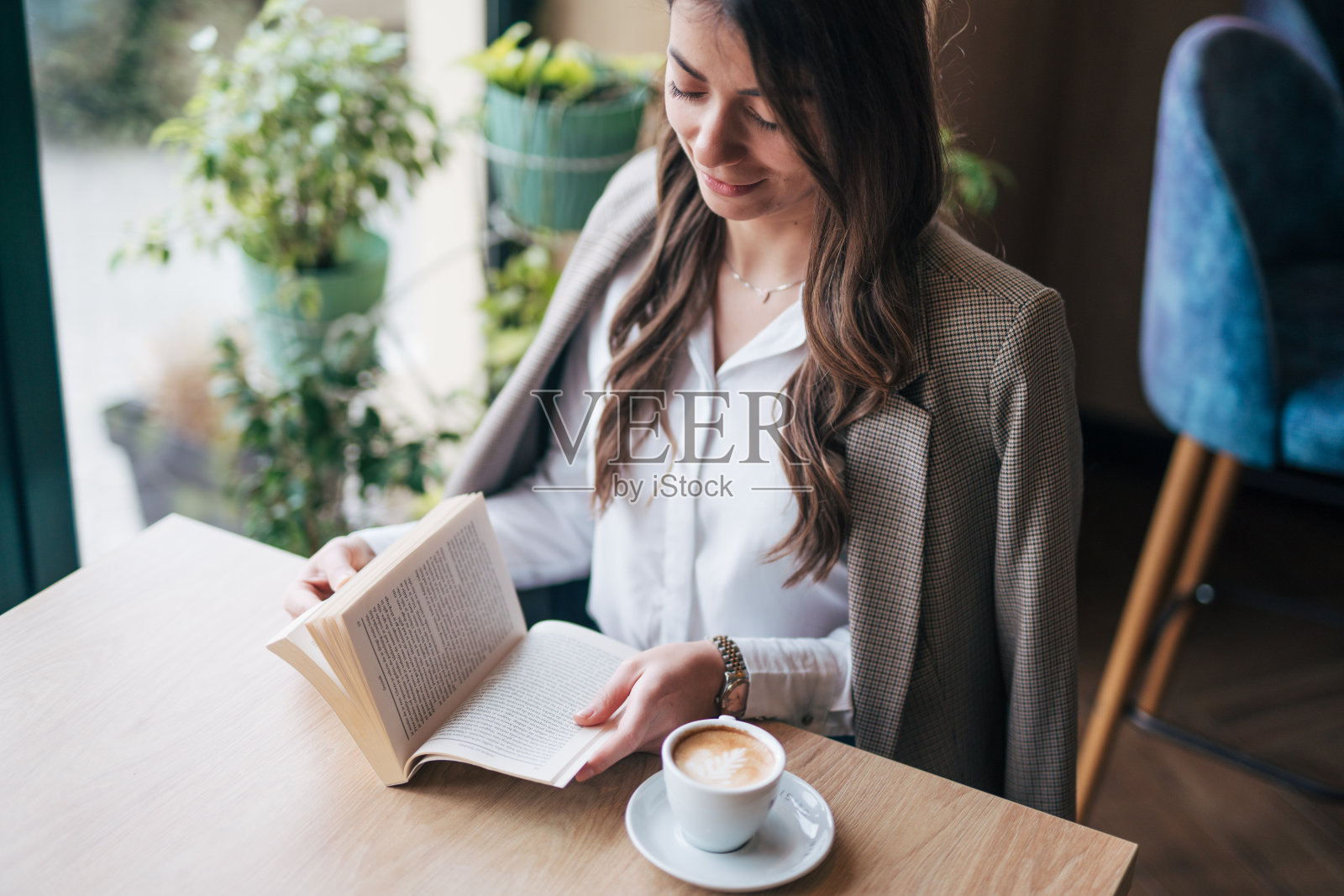 年轻女子坐在咖啡馆里看书照片摄影图片
