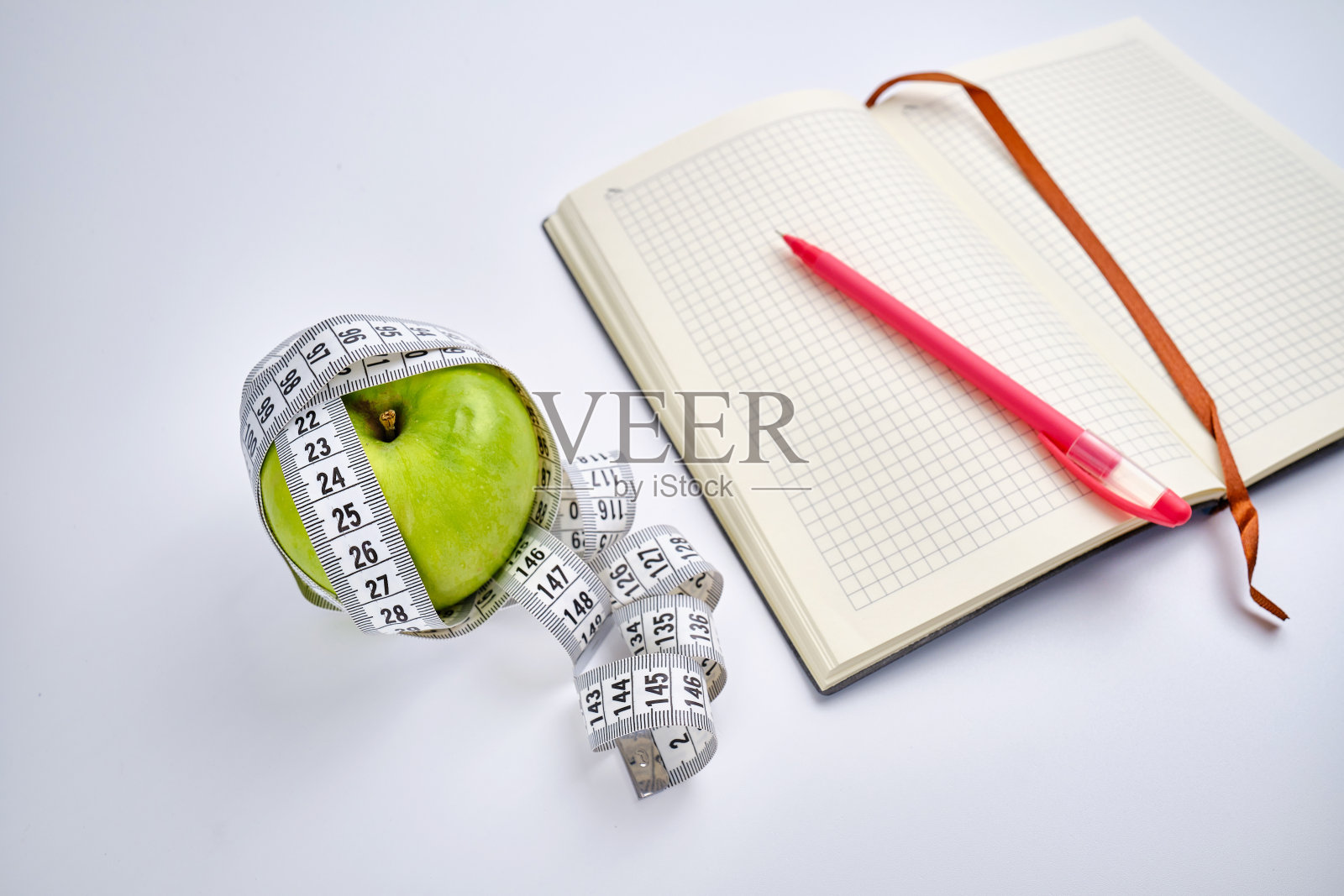 白色厘米，打开的记事本和绿色的苹果在一个彩色的背景。健康饮食，卡路里含量。营养、身材、健康的理念照片摄影图片