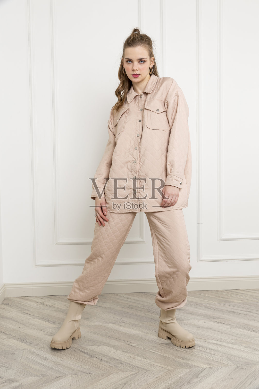 穿着奶油色毛衣和运动裤的金发女郎。照片摄影图片