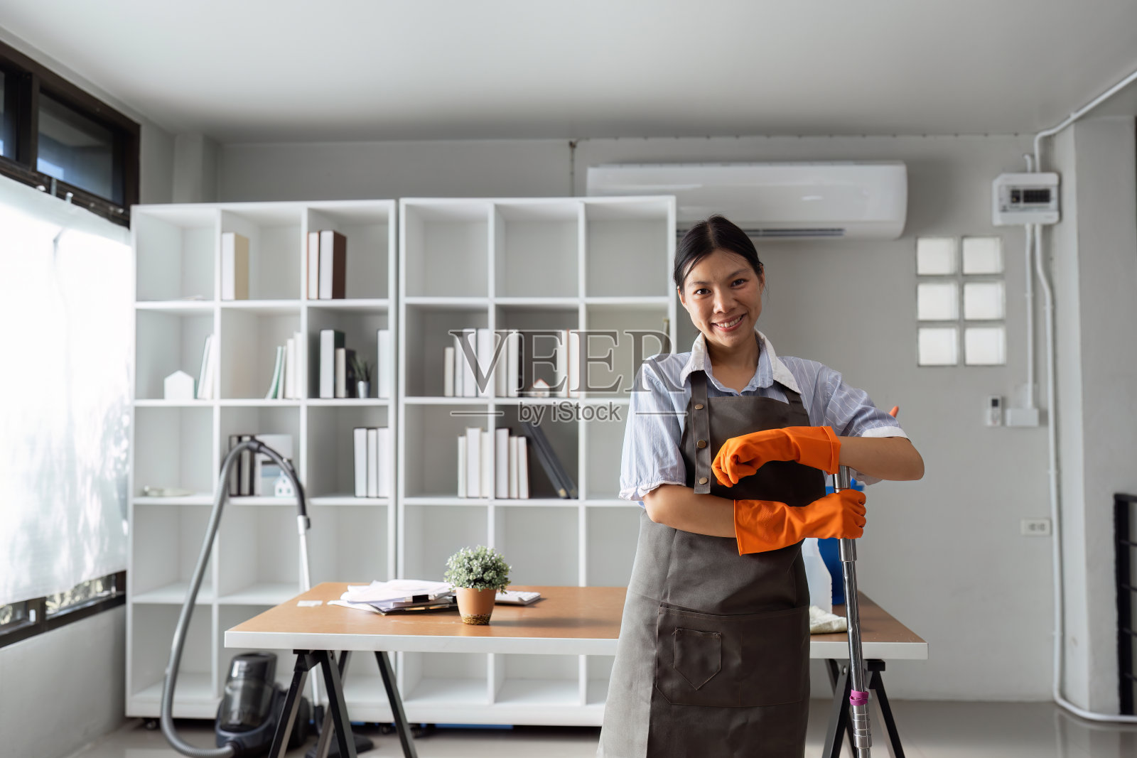 女管家面带微笑，戴着手套，准备打扫办公室照片摄影图片