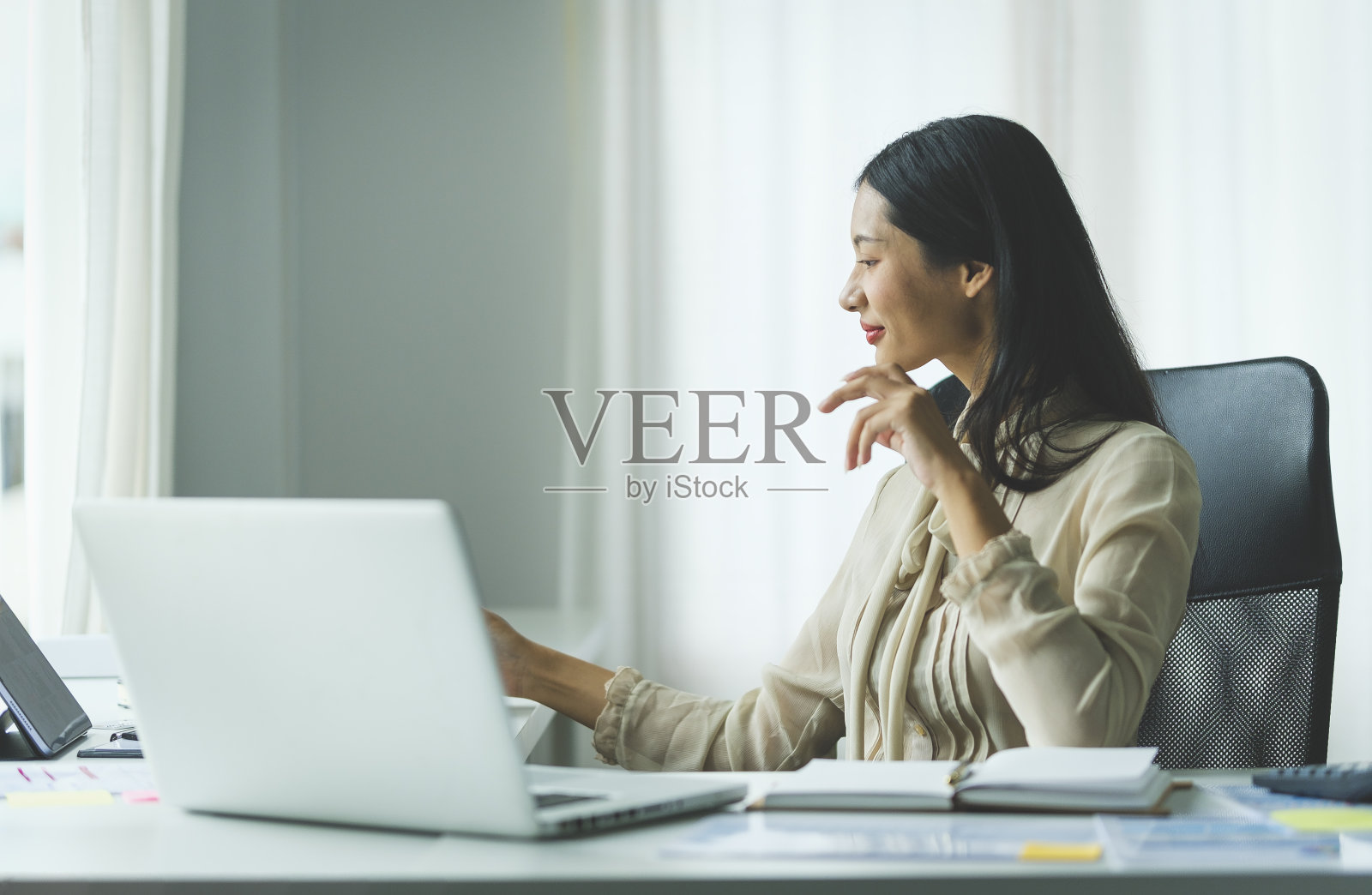 迷人的年轻女商人在她的工作站使用笔记本电脑。照片摄影图片