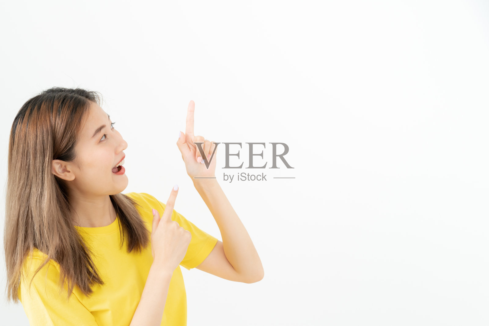 肖像亚洲美丽的女孩指向空白孤立的背景。快乐的女人指着什么。年轻女性站在旁边指指点点，广告牌，介绍，广告，空间照片摄影图片