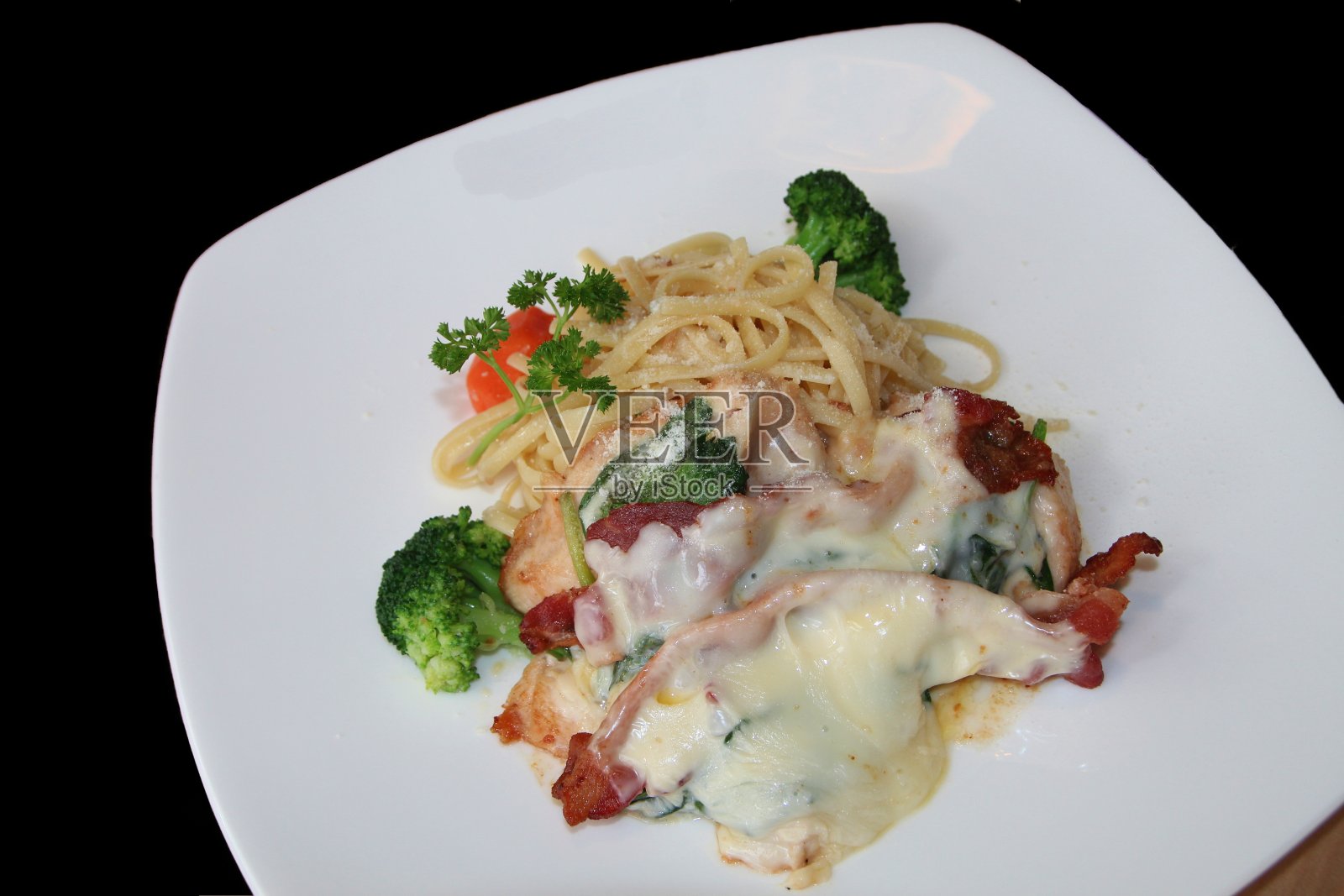 白色盘子里的意大利面条加培根和西兰花。照片摄影图片