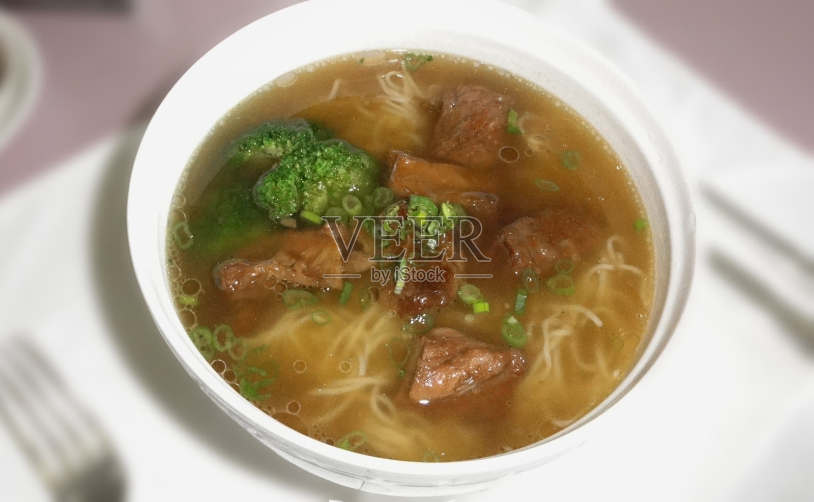 白碗牛肉花椰菜面汤。照片摄影图片