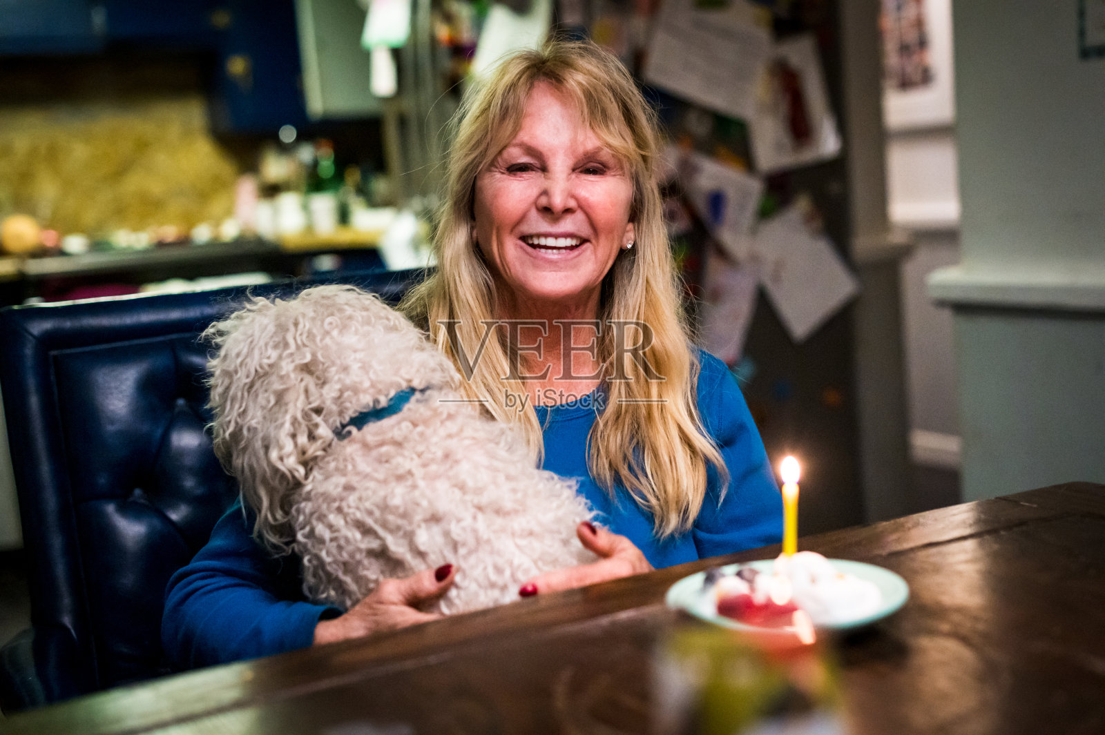 一个60多岁的成熟女人在家里吃着生日蛋糕，带着她的宠物狗过生日照片摄影图片