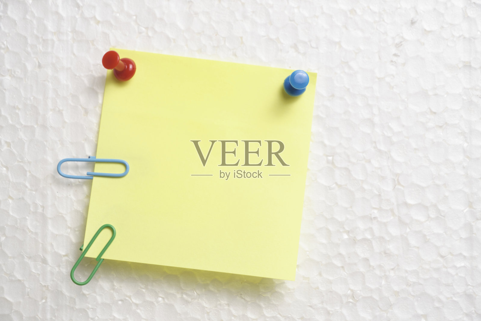 墙上挂着帮助文具按钮的黄色贴纸是用来做笔记的。照片摄影图片