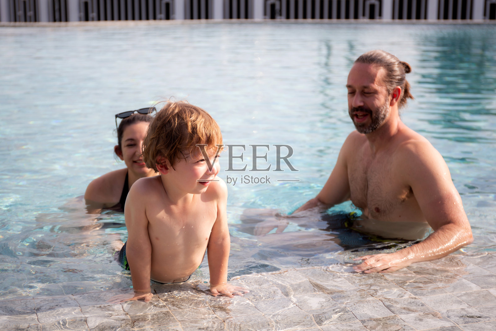 白种人家庭在游泳池里享受快乐，夏日和假期，妈妈，爸爸和儿子放松和玩耍，夏日和假期，关系和纽带，家庭概念。照片摄影图片