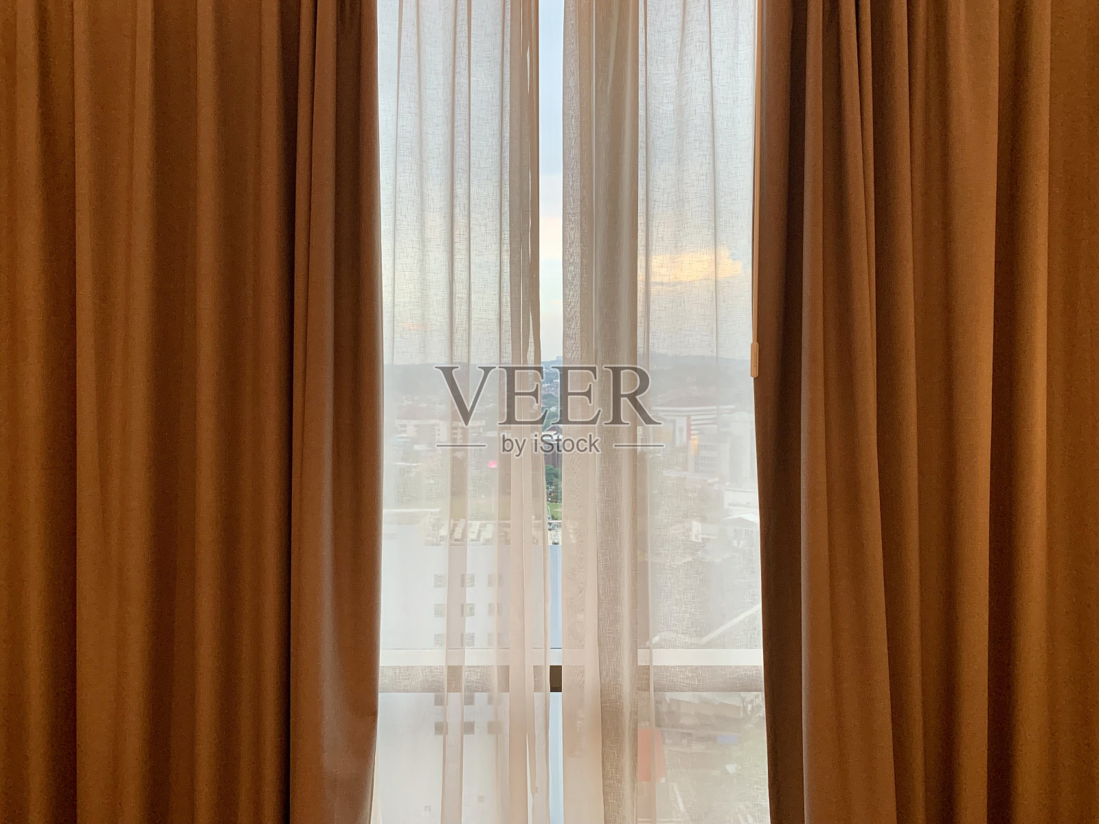 酒店房间窗帘后的城市景观照片摄影图片