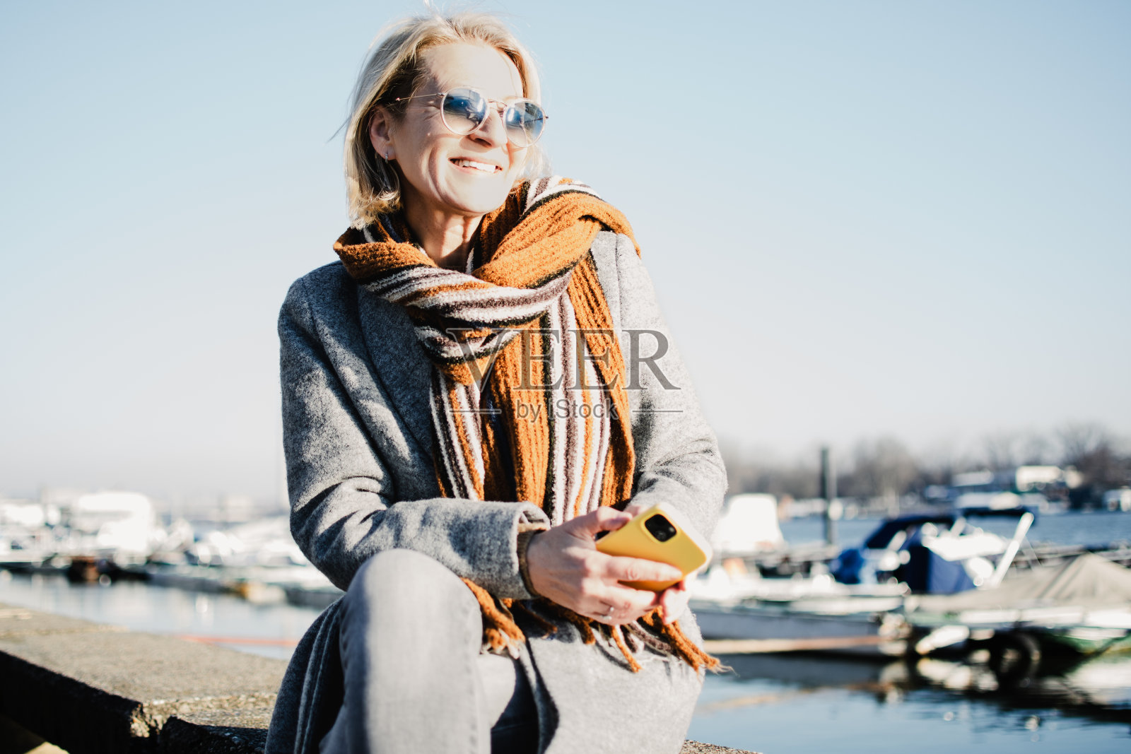 一位戴着墨镜的成熟金发女子坐在河岸上照片摄影图片