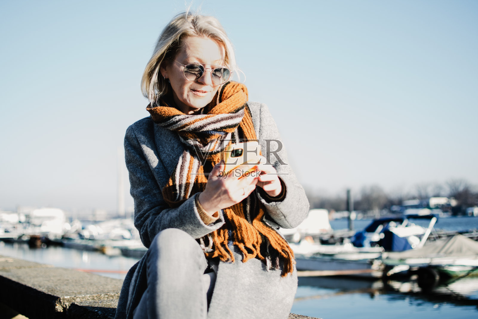 一位戴着墨镜的成熟金发女子坐在河岸上照片摄影图片