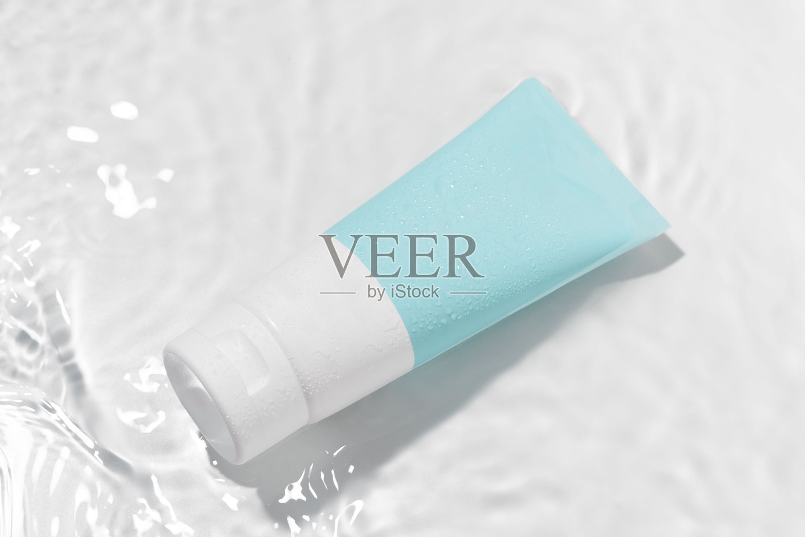 一个蓝色和白色的空白模拟管保湿霜在波浪在白色的背景。天然美容产品及面部及身体护肤的概念照片摄影图片