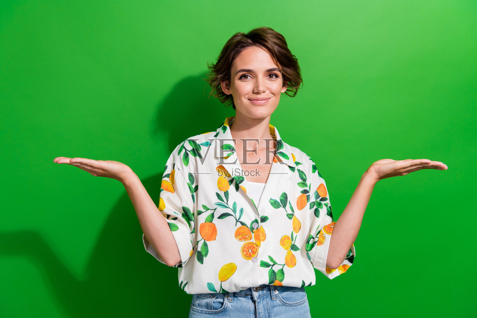 可爱开朗的女孩穿着时髦的衣服，在绿色背景上呈现出两种孤立的解决方案照片摄影图片