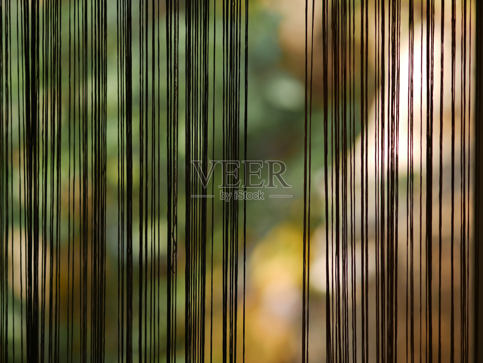 在阳光明媚的日子里，以绿色灌木为背景的垂直线条形式的窗帘。透过玻璃门观看。高雅的家居装饰。2024年1月23日，克罗地亚伊斯特拉罗维尼照片摄影图片