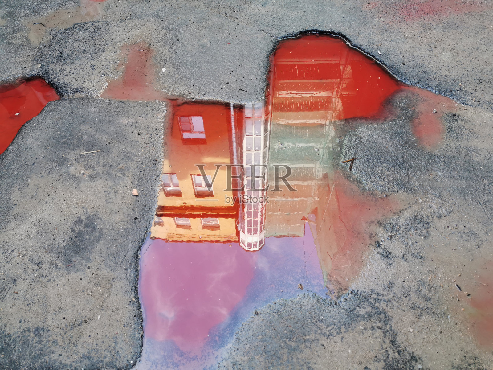 灰色沥青城市街道道路上红色水坑表面的房屋倒影照片摄影图片