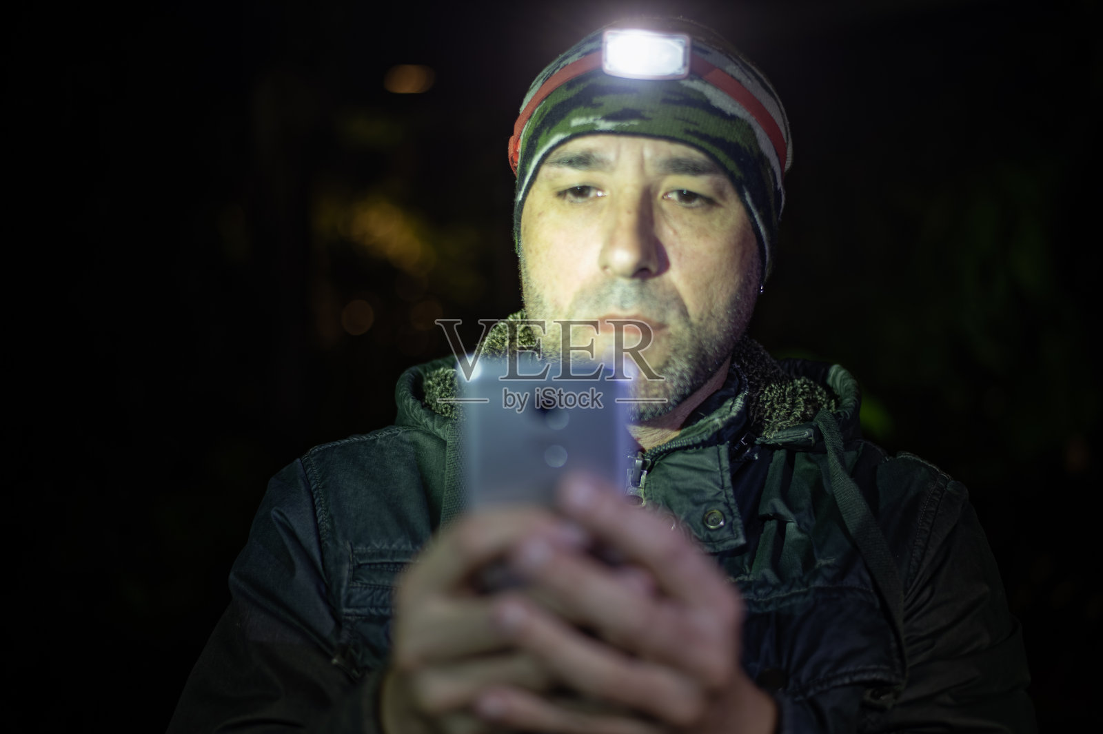 探险旅行者在他的智能手机上查看他夜间散步的地图。照片摄影图片