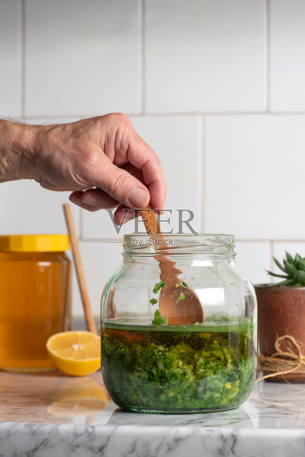 一名男子正在用麝香草的叶子和蜂蜜配制健康的酊剂照片摄影图片