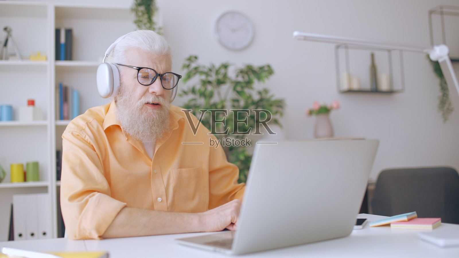 一位60多岁的老人在家里用笔记本电脑看视频，平衡学习和动力照片摄影图片