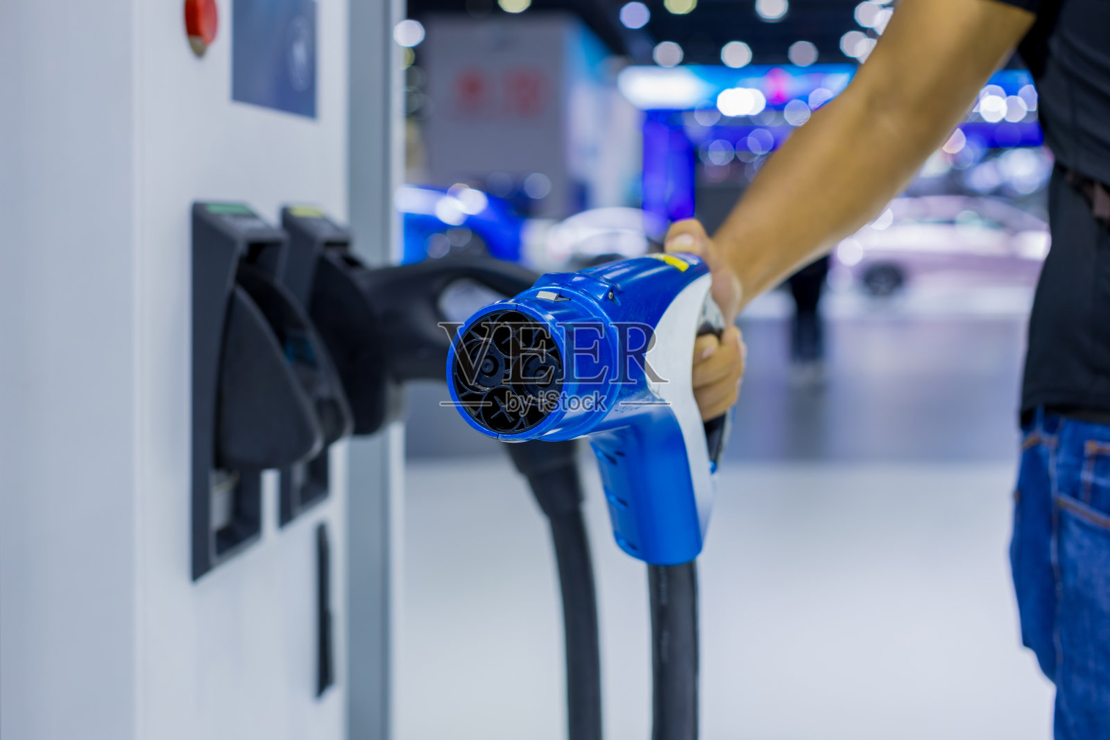 手动插入电动汽车充电插头。电动汽车的司机插入电连接器给电池充电。照片摄影图片