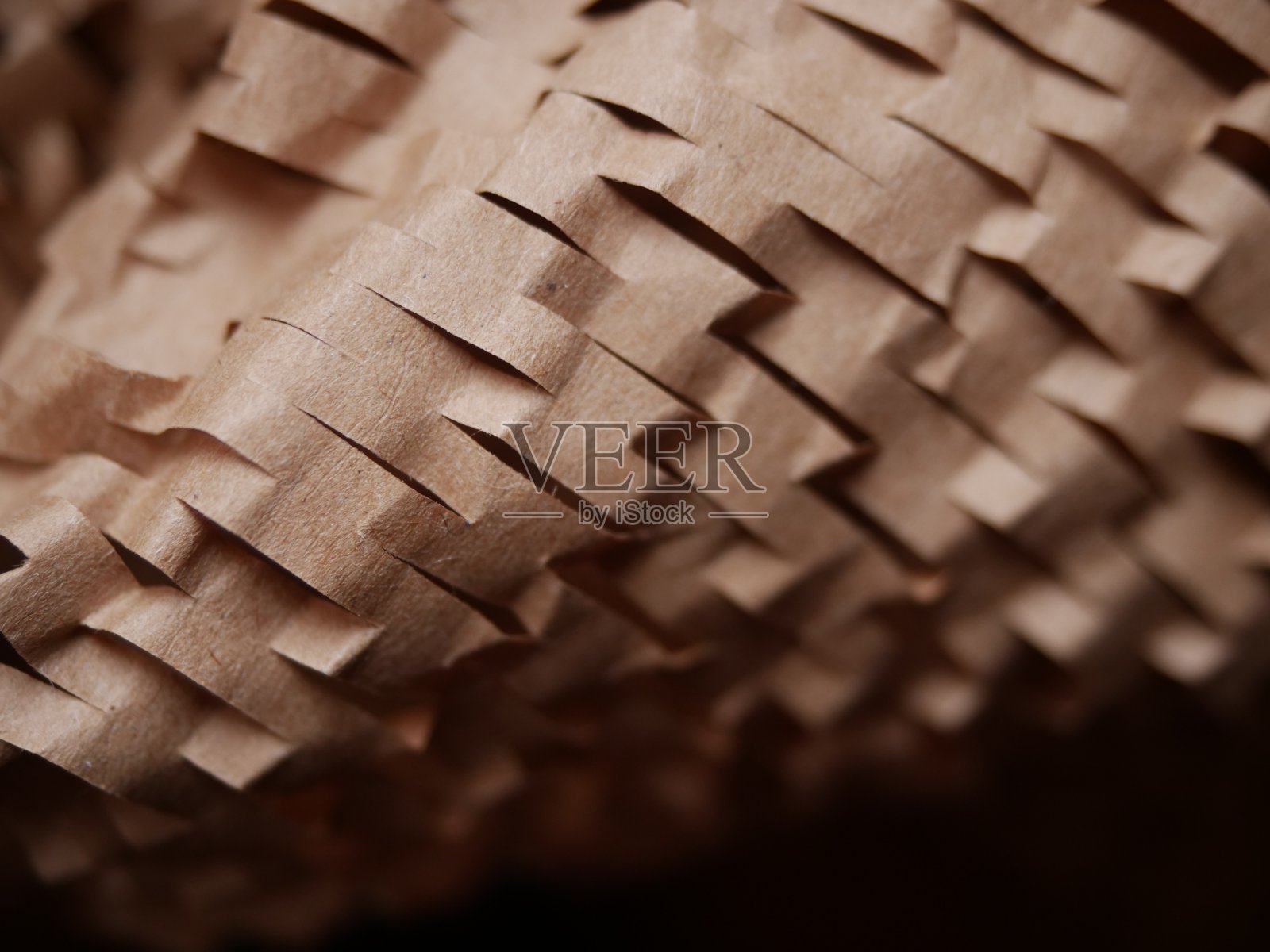 包裹的填充物。带槽的牛皮纸棕色蜂窝包装纸。把皱巴巴的纸凑近一点。回收的建筑用纸。放文字的地方。Copyspace。纹理背景。有选择性的重点照片摄影图片