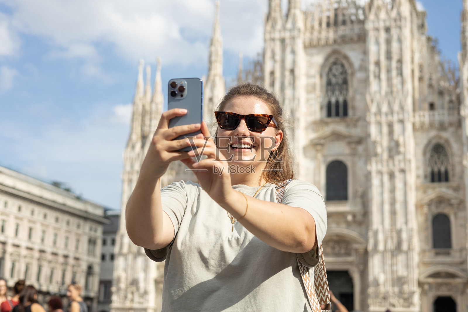 年轻快乐的游客在米兰著名的大教堂前自拍。夏天去欧洲旅游。有魅力的女性正在探索城市，游客用智能手机拍照或录像照片摄影图片