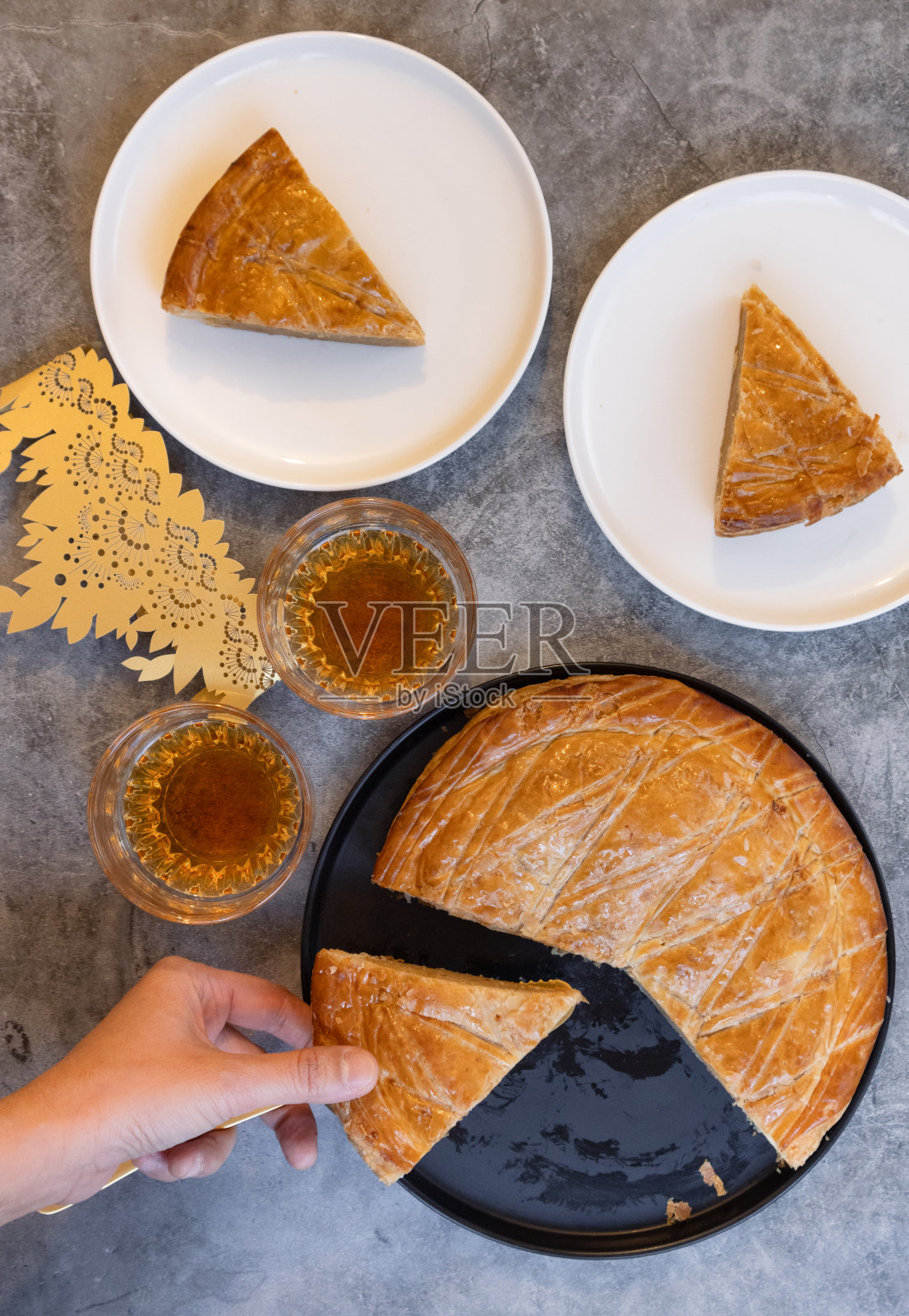 俯视图的法国galette des rois与它的一块在盘子里，手抓一块与手柄的蛋糕切片机照片摄影图片