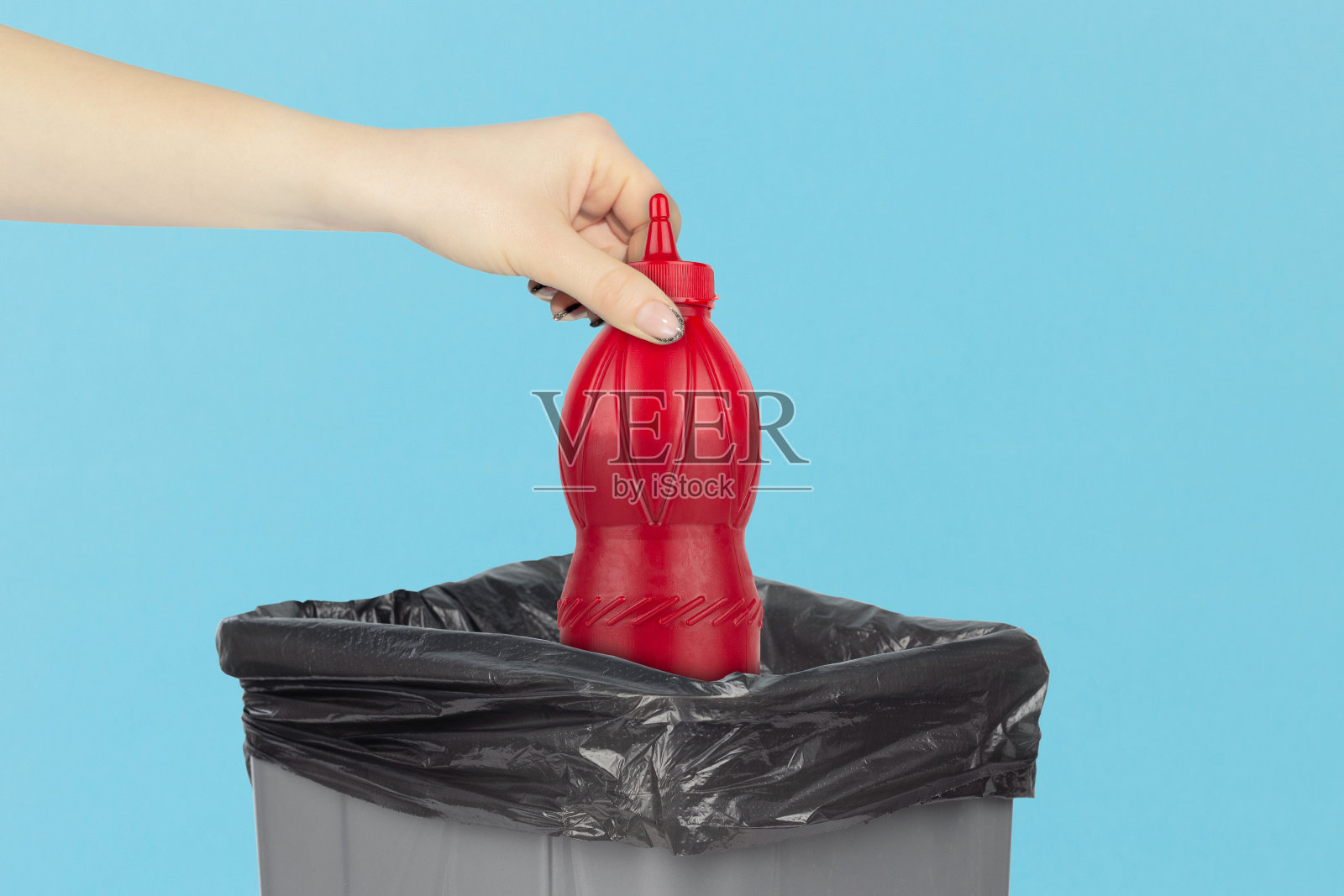 把一罐番茄酱扔进垃圾桶，手里拿着一罐番茄酱放在垃圾桶前，循环利用的概念照片摄影图片