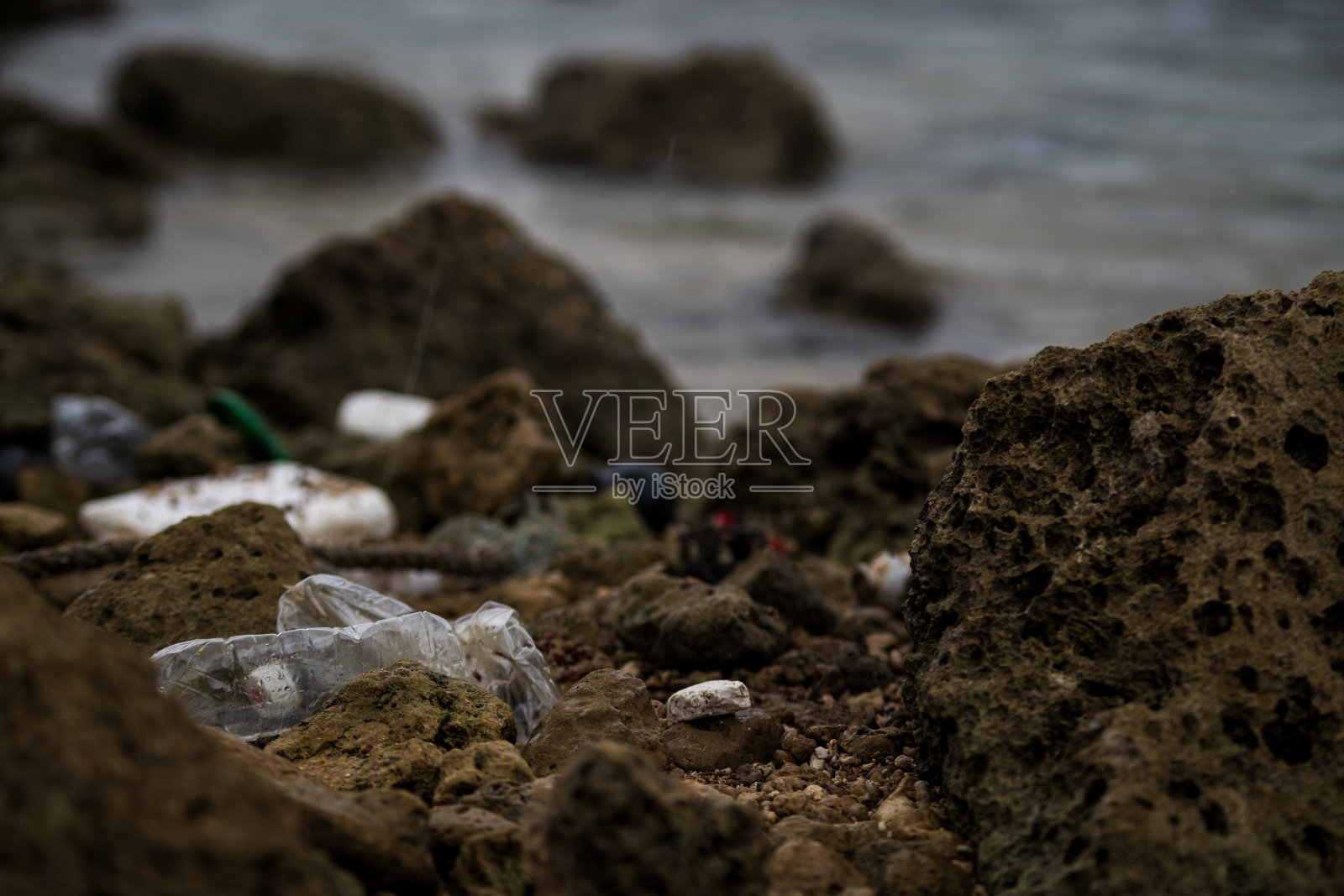 访问亚洲的外国男子清理海滩上的塑料垃圾。照片摄影图片