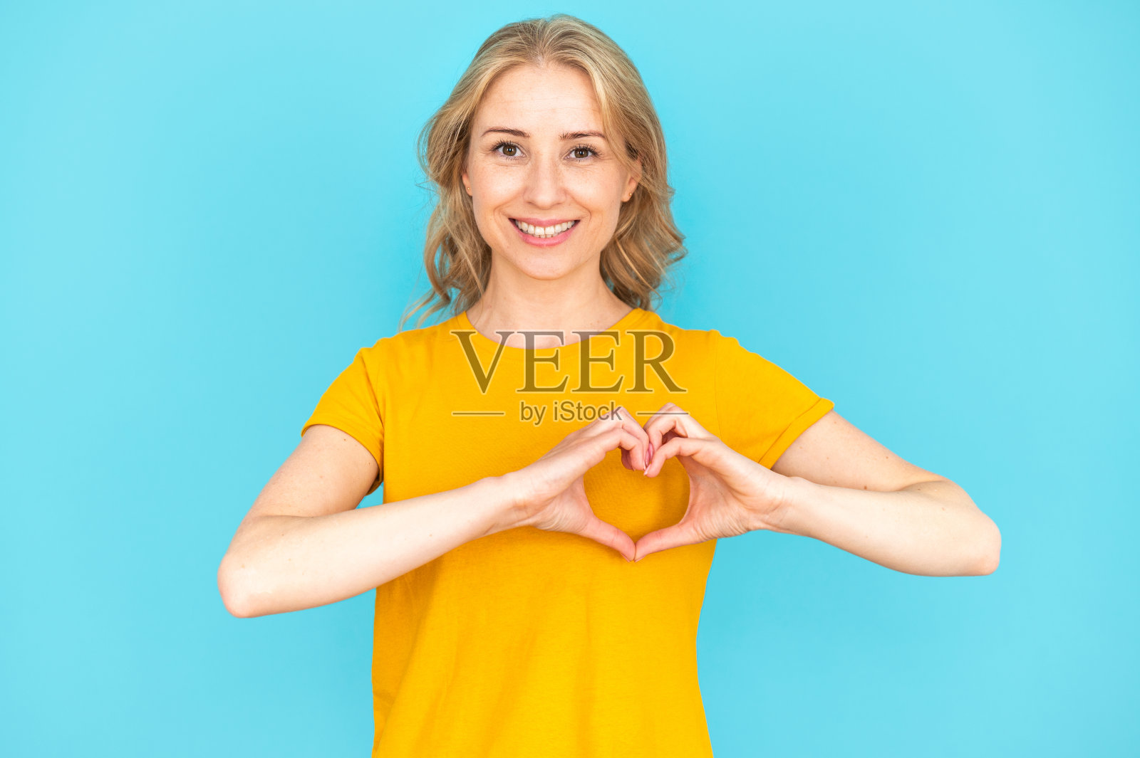 年轻女子做心形手势，双手放在胸前照片摄影图片