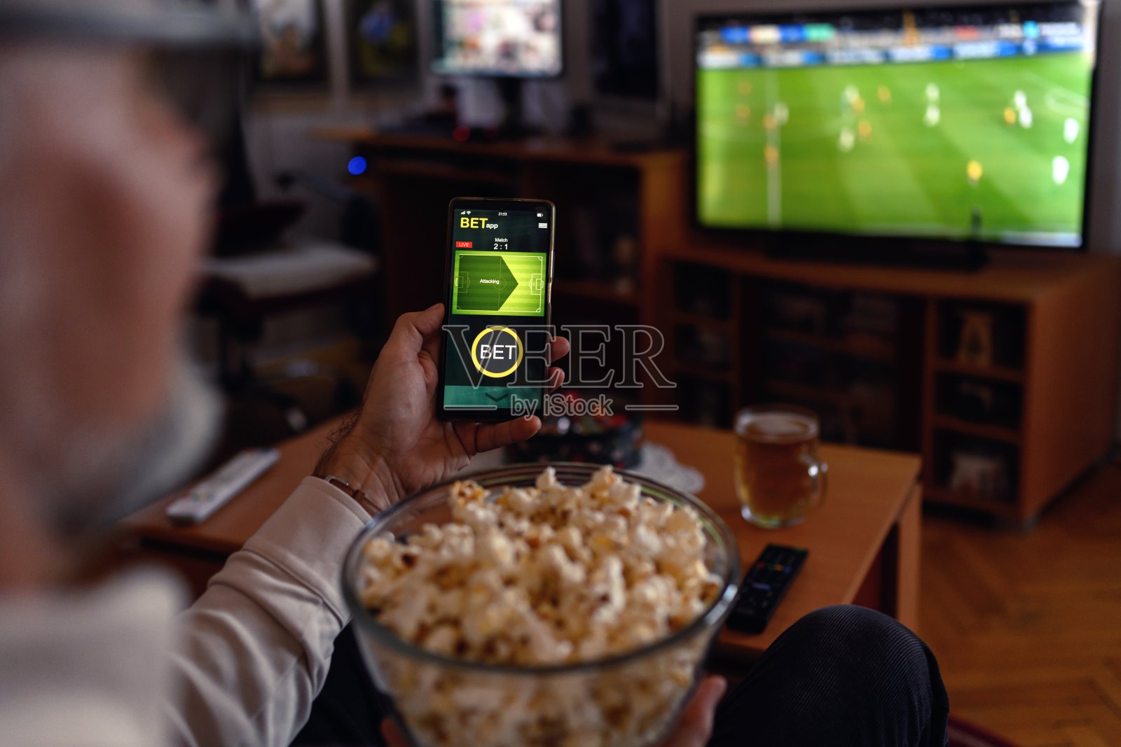 成熟男人用智能手机进行体育博彩。照片摄影图片