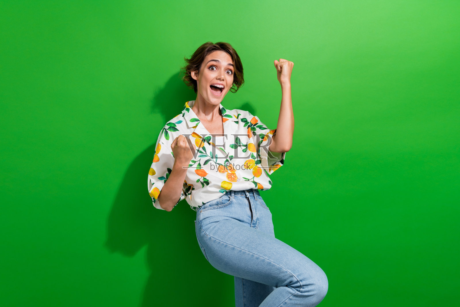 照片积极幸运的女孩穿着印花衬衫上升的拳头尖叫耶孤立的绿色背景照片摄影图片