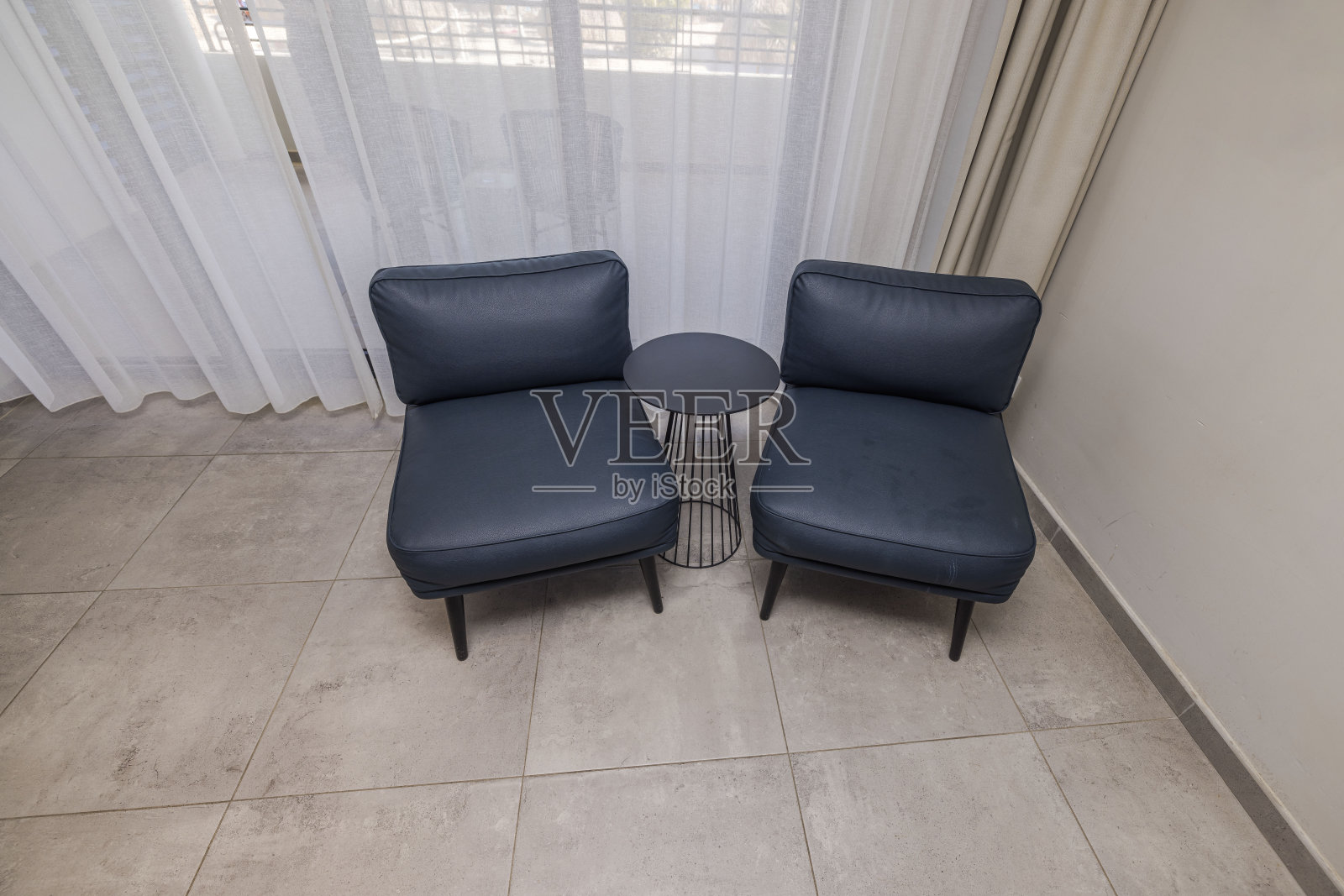 在酒店房间的角落里，两张椅子中间有一张桌子，这是一张美丽的室内景色。库拉索岛。照片摄影图片