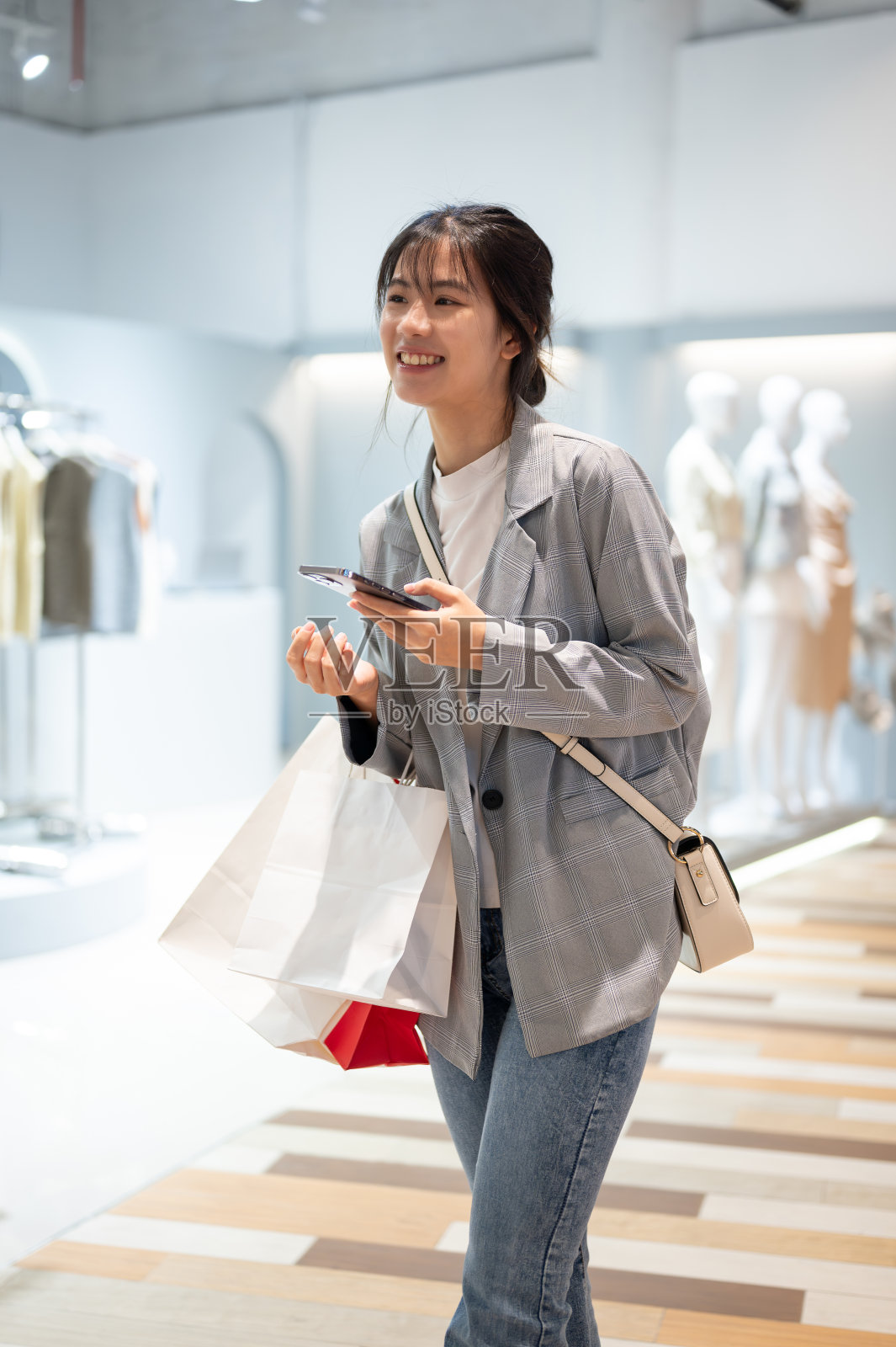 一位带着购物袋的亚洲美女正在购物中心享受购物的乐趣。照片摄影图片