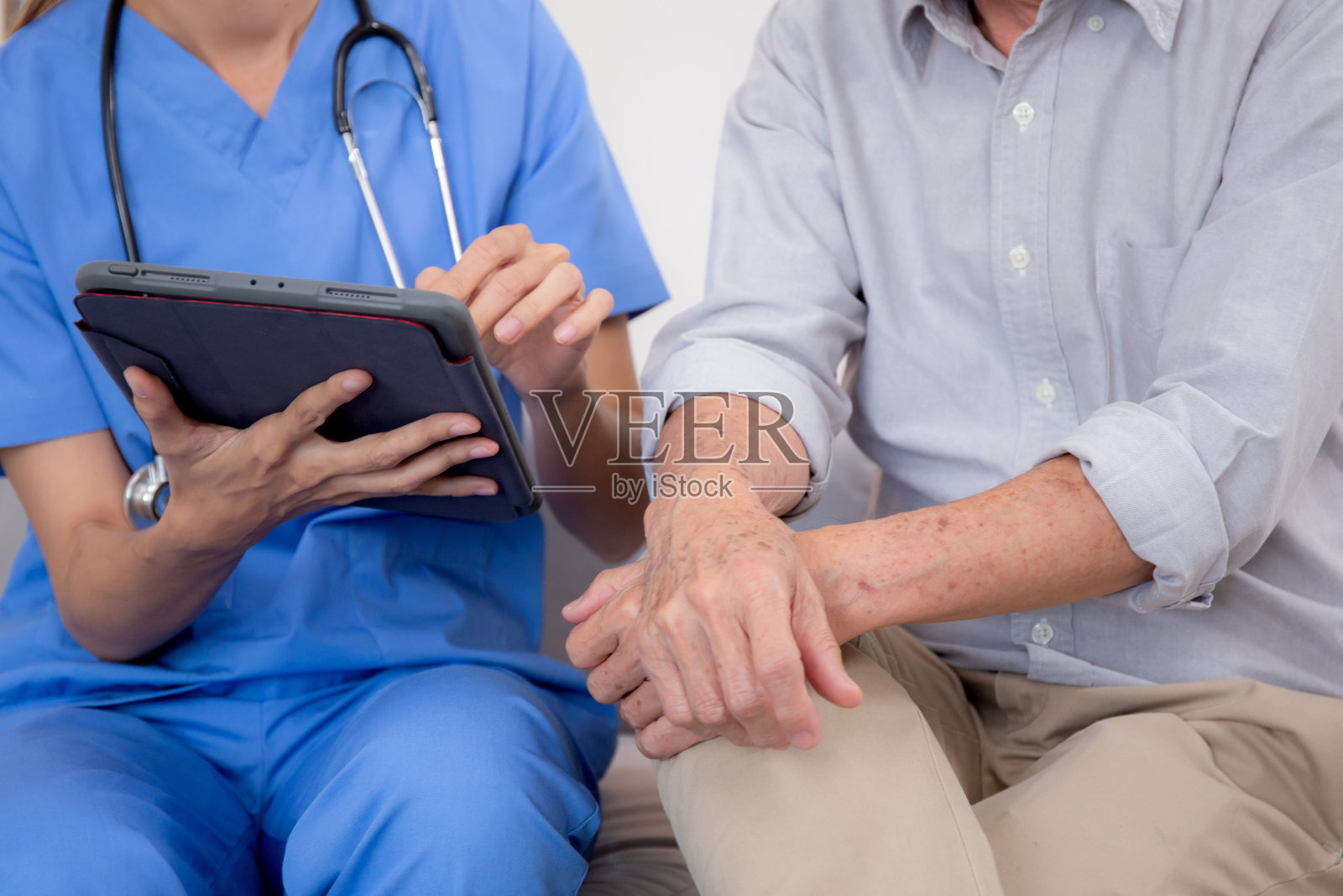 坐在沙发上的看护者为家中客厅的老年患者进行健康检查和诊断，坐在沙发上的看护者解释和检查老年人、保险和医疗。照片摄影图片