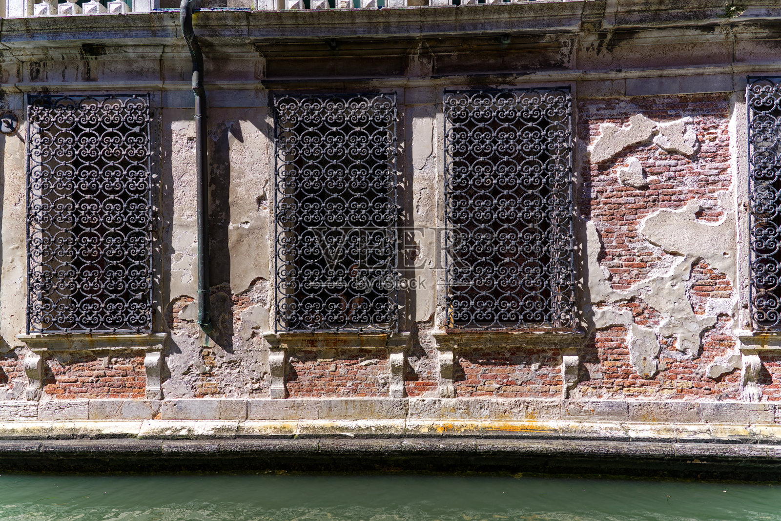 欧洲著名城市威尼斯的外墙特写，砖墙和破碎的灰泥，有保护的窗户。照片摄影图片