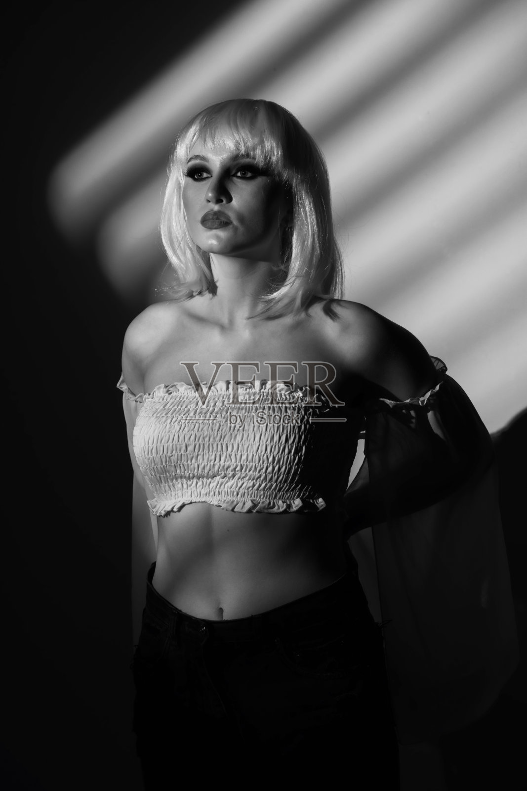 美丽的女人黑白肖像，戴着白色的假发，透过百叶窗被光线照亮照片摄影图片