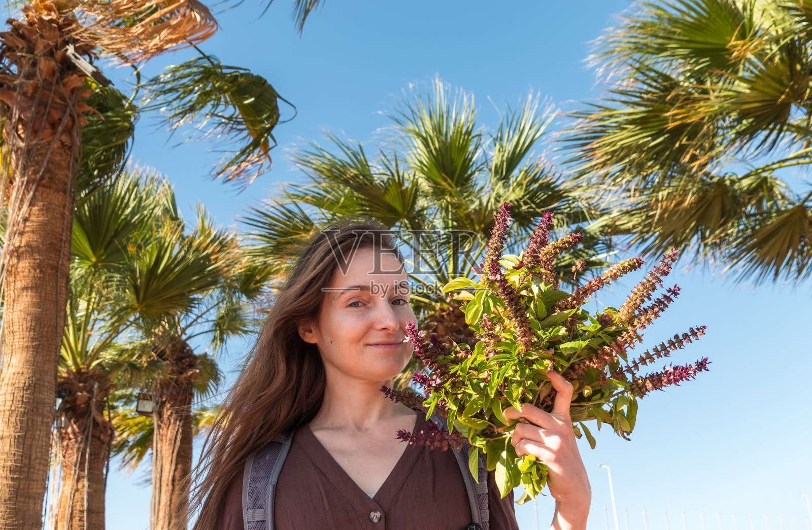 快乐的年轻女子脸上带着兴奋的表情，手捧罗勒花束，夏季度假概念照片摄影图片