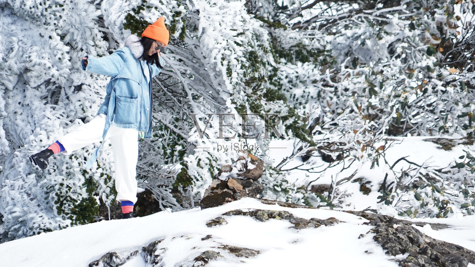 一个女人在寒冷的天气里穿行于白雪覆盖的山林之中照片摄影图片