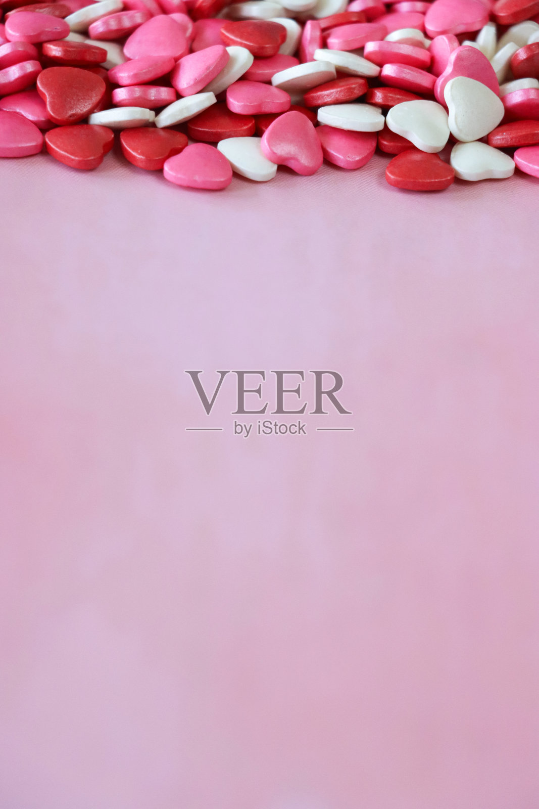 形象情人节设计海报框架由红色、粉色和白色心形糖果打造，情人节装饰，斑驳的粉色背景，抬高视野，情人节和浪漫的概念，复制空间照片摄影图片